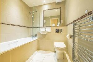 a bathroom with a toilet and a tub and a sink at Holyrood Aparthotel in Edinburgh