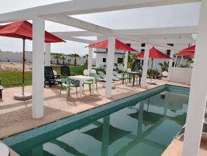 a pool with tables and chairs and umbrellas at Riad Sahara Sunset Beach Douira Agadir in Douaïra
