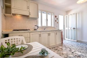 a kitchen with white cabinets and a table and a sink at Magic Sea View Borgo Castelsardo in Castelsardo
