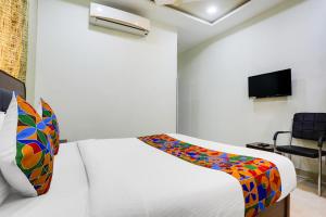 ein weißes Schlafzimmer mit einem Bett und einem Fernseher in der Unterkunft FabHotel Johar Inn in Raipur