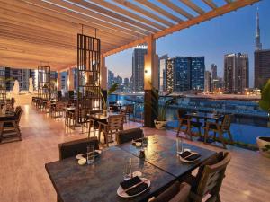 Hyde Hotel Dubai في دبي: مطعم بطاولات وكراسي وإطلالة على المدينة