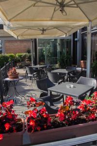 een patio met tafels, stoelen en bloemen bij Hotel Pico in Mirandola