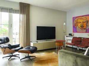 a living room with a flat screen tv and chairs at Holiday Home Bungalowpark It Wiid by Interhome in Eernewoude