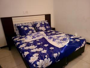 a bed with a blue and white comforter and pillows at Furnished Luxury 2-bedroom apartment -Vanguard X ,Cloud 9 in Douala