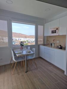 a kitchen with white cabinets and a table and a window at Alojamientos Agaete Pueblo Nº6 in Agaete