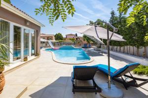 a pool with a chair and an umbrella at Five bedroom villa Emily with pool in Medulin in Medulin