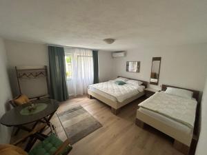 a bedroom with two beds and a table and a window at Miles Apartment in Ohrid