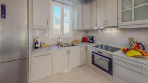 a kitchen with white cabinets and a sink at Leonidas Family Apartment 1 in Pómbia