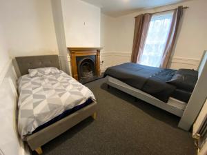 a bedroom with two beds and a fireplace at Southgate Lodge - Single-Twin, Double and Family rooms in Kings Lynn