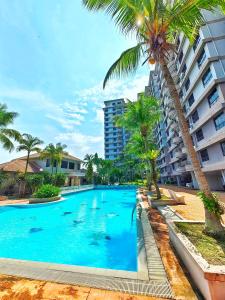 une piscine avec des palmiers et un bâtiment dans l'établissement Klebang GX Homestay City & Partial Seaview P0805 with Youtube, TV Games & Toys, à Malacca