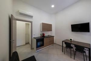 a kitchen with a table and a tv on the wall at Casa Vacanze Nemesi TYCHE in Salerno +3 photos