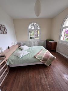 ein Schlafzimmer mit einem Bett und einem Schreibtisch und zwei Fenstern in der Unterkunft LouiseHélène in Merville-Franceville-Plage