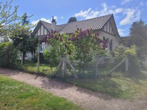 einen Zaun vor einem Haus mit Blumen in der Unterkunft LouiseHélène in Merville-Franceville-Plage