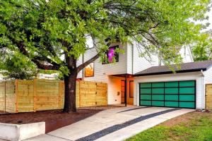 uma casa branca com portas verdes de garagem e uma árvore em Hot Tub Club - Rainey Street - 6 min walk em Austin