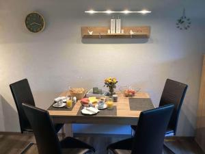 Una mesa de comedor con sillas y un reloj en la pared. en Ferienwohnung Harzer Sonnenbaum, en Sankt Andreasberg
