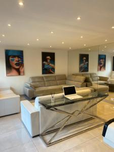 un salon avec un canapé et un ordinateur portable sur une table en verre dans l'établissement VILLA OCEANE, à Cannes