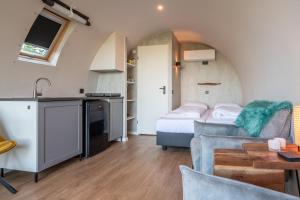 a kitchen and a living room with a bed and a couch at Tiny Wellnesslodge Wulp met sauna in Dalerveen