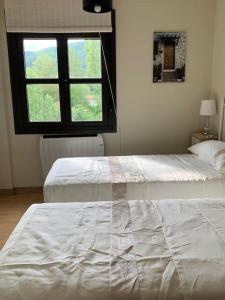 a bedroom with two beds and a window at Alojamiento fiordos leoneses Boñar in Boñar