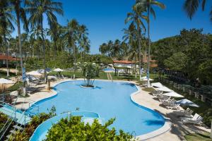 a pool with chairs and umbrellas at a resort at Fazenda Fiore Resort in Paripueira