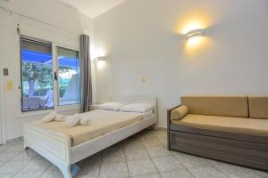 a bedroom with a bed and a couch and a window at Epavlis Beach Resort in Porto Heli +110 photos
