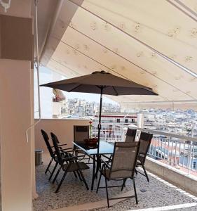 a table and chairs with an umbrella on a balcony at Kavala Penthouse in Kavala