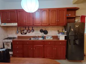 a kitchen with wooden cabinets and a black refrigerator at TropicalHouse in Punta Cana