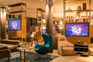 ミュンヘンにあるモーテル ワン ミュンヘン パルクシュタット シュヴァービングの青い椅子とテレビ2台が備わるロビー
