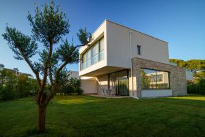 a white house with a tree in the yard at SanPietro Vacation Rentals in Draç