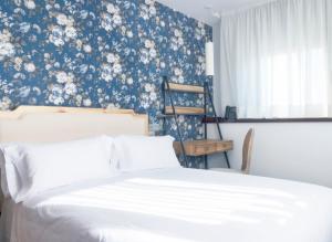 a bedroom with a bed with a blue and white floral wallpaper at Christine Boutique Hotel in El Barraco
