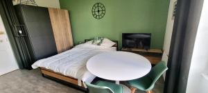 una camera da letto con un tavolo, un letto bianco e una TV di Vittel Studio neuf pour cure ou longue durée a Vittel