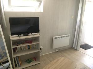 un salon avec une télévision et une étagère à livres dans l'établissement Au calme, proche gare, à Brive-la-Gaillarde