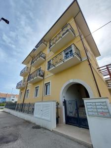 a yellow building with balconies on the side of it at Casa Vacanze CuprAmare in Cupra Marittima
