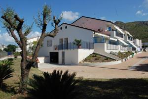 a white house with a tree in front of it at Residenza Le Spiagge in Sperlonga