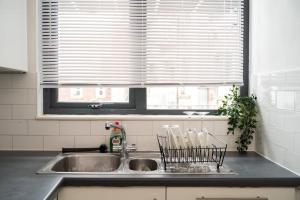 eine Küchentheke mit Spüle und Fenster in der Unterkunft Modern City Centre 2 Bed Apt in Leeds & Netflix & Hammock in Leeds