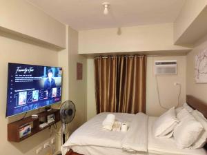 a hotel room with a bed and a flat screen tv at 711 Tower 3 Avida Atria Iloilo Comfy Cozy Central in Iloilo City +7 photos