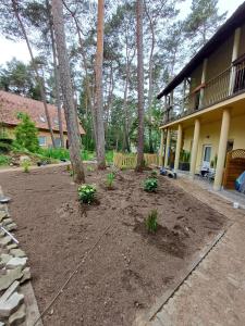 a yard with trees and a house with a patio at Bursztyn 2 in Pobierowo