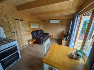 a kitchen and living room with a stove and a table at Meadow Lodge in Billericay