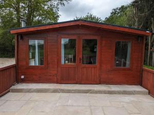 a wooden cabin with glass doors on a patio at Meadow Lodge in Billericay