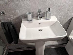 a white sink in a bathroom with black towels at Meadow Lodge in Billericay