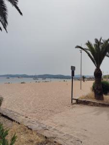 a beach with a palm tree and a sign on it at T3 avec piscine et proche de la mer 5mns à pied in Saint-Raphaël