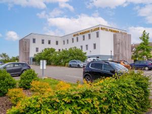 a building with cars parked in a parking lot at Première Classe Chartres Sud - Barjouville in Chartres