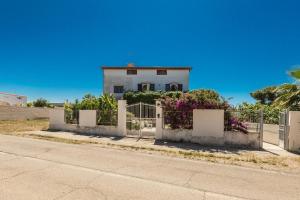 ein weißes Haus hinter einem Zaun mit lila Blumen in der Unterkunft Villa Edera by BarbarHouse in Marina di Lizzano