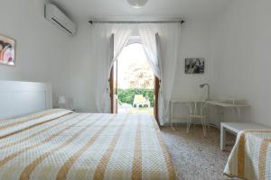 ein weißes Schlafzimmer mit einem Bett und einem Fenster in der Unterkunft Villa Edera by BarbarHouse in Marina di Lizzano