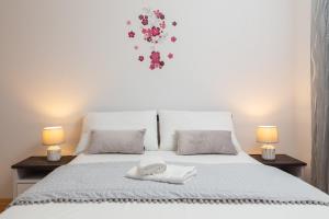 ein weißes Bett mit zwei Lampen und einem weißen Handtuch darauf in der Unterkunft Sunshine Holiday Home in Kaštela