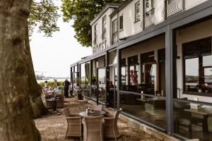 a building with tables and chairs next to a tree at Hotel Restaurant Belvédère in Schoonhoven