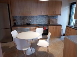 cocina con mesa blanca y sillas blancas en Mary House, en Pefkali 10 fotos más