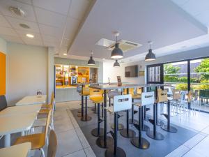 a restaurant with tables and chairs in a cafeteria at Premi&egrave;re Classe Chartres Sud - Barjouville in Chartres