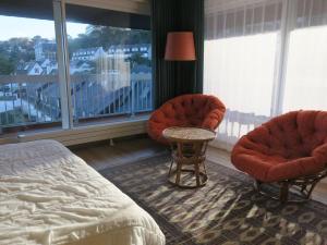 a bedroom with two chairs and a bed and a window at Appartement à Perros-Guirec avec Vue Panoramique, Terrasse et Parking Privé - FR-1-368-271 in Perros-Guirec