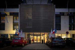 um edifício com dois carros estacionados em frente em Nemea Appart Hotel Stadium Bordeaux aéroport em Mérignac