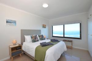 a bedroom with a bed and a large window at Seaforever Apartment in Yzerfontein